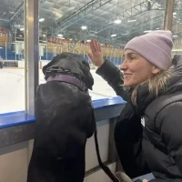 Dawn, ounder of High Park Pet Care, at a hockey game with a black dog